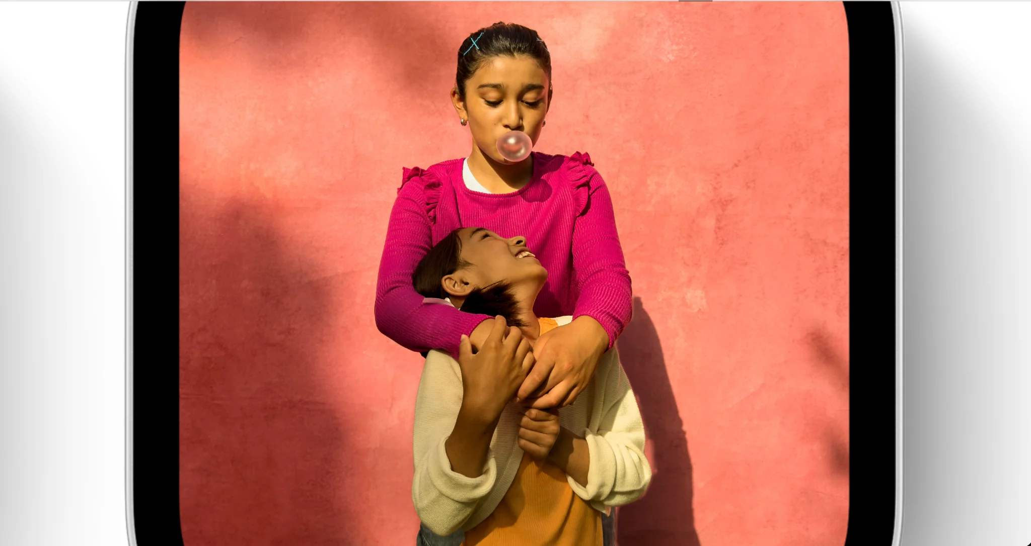 Detailed view of a screen showing two children against a pink background